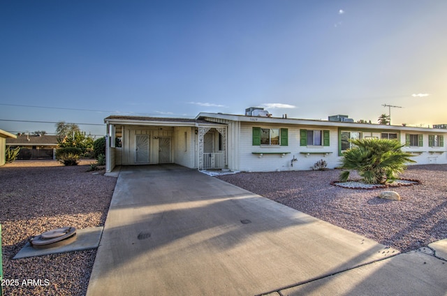 ranch-style house with brick siding, concrete driveway, and a carport