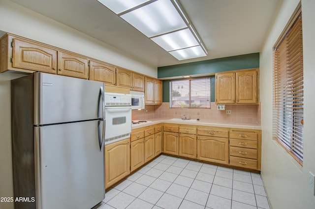 kitchen featuring decorative backsplash, white appliances, light tile patterned flooring, and a sink