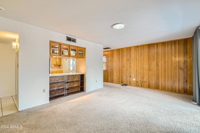 unfurnished living room with wood walls and light colored carpet