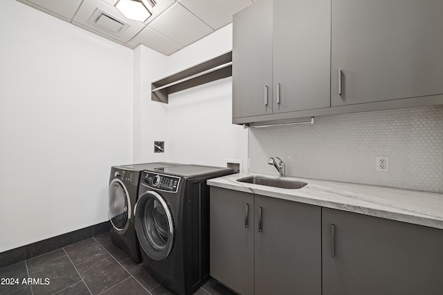 laundry area with cabinets, dark tile patterned floors, washer and clothes dryer, and sink