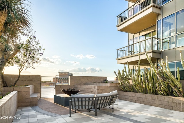 patio terrace at dusk with outdoor lounge area and a balcony