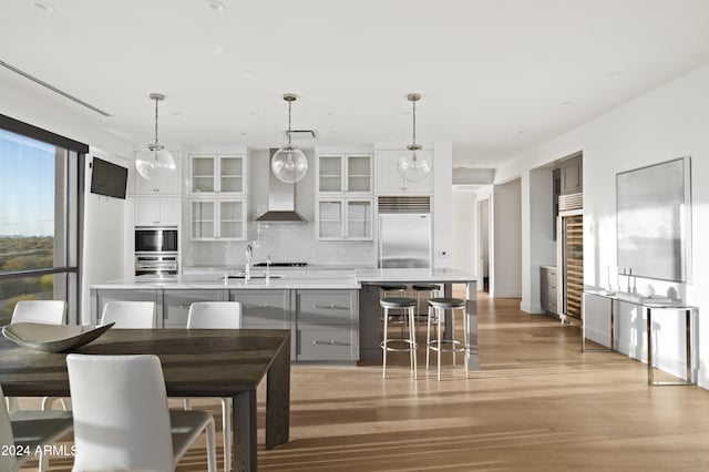 kitchen with hanging light fixtures, built in fridge, light hardwood / wood-style floors, gray cabinets, and white cabinets