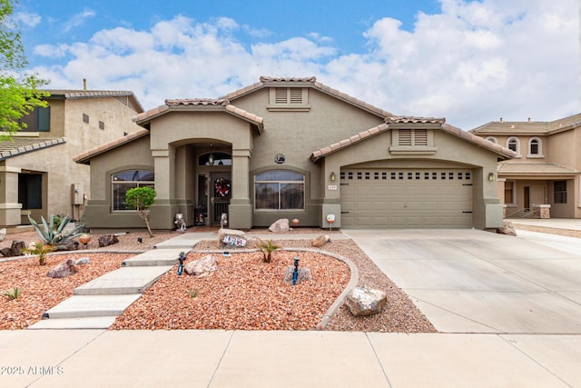 mediterranean / spanish home featuring stucco siding, a tile roof, driveway, and a garage