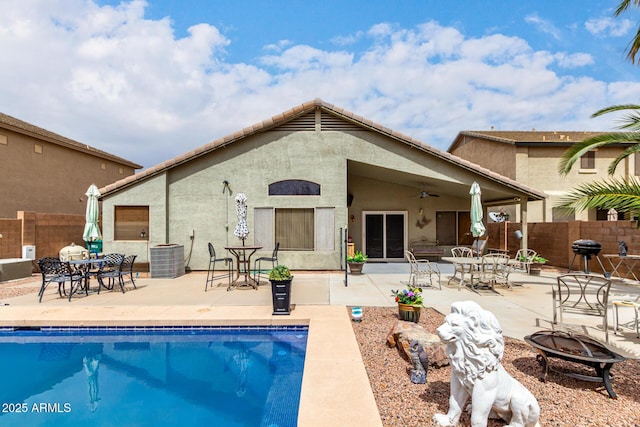 rear view of property featuring a fire pit, fence, a fenced in pool, and ceiling fan