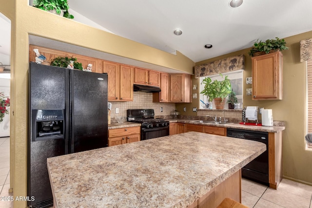 kitchen featuring lofted ceiling, under cabinet range hood, light tile patterned floors, a sink, and black appliances