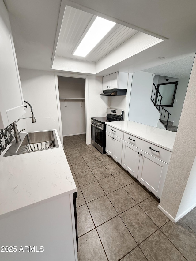 5975 N 48th Dr, Glendale, AZ 85301 - kitchen featuring stainless steel electric stove, a sink, under cabinet range hood, light tile patterned floors, and white cabinetry