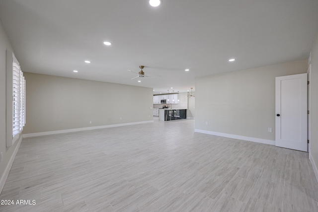 unfurnished living room featuring ceiling fan and light hardwood / wood-style floors