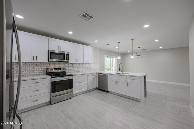 kitchen featuring decorative light fixtures, sink, stainless steel appliances, kitchen peninsula, and white cabinetry