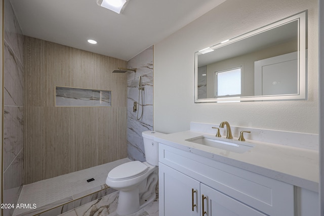 bathroom with vanity, toilet, and tiled shower