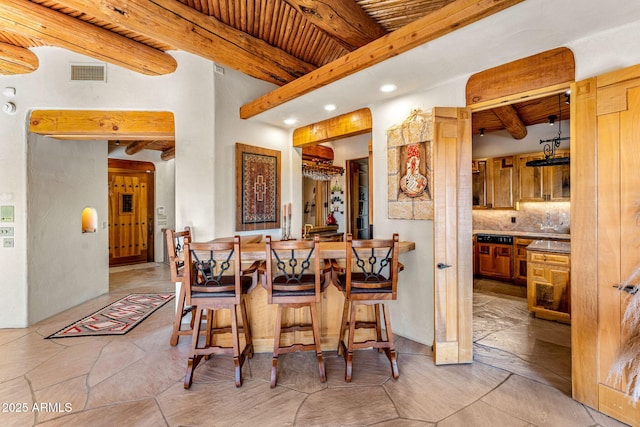 interior space featuring tasteful backsplash, a kitchen bar, wooden ceiling, and beam ceiling