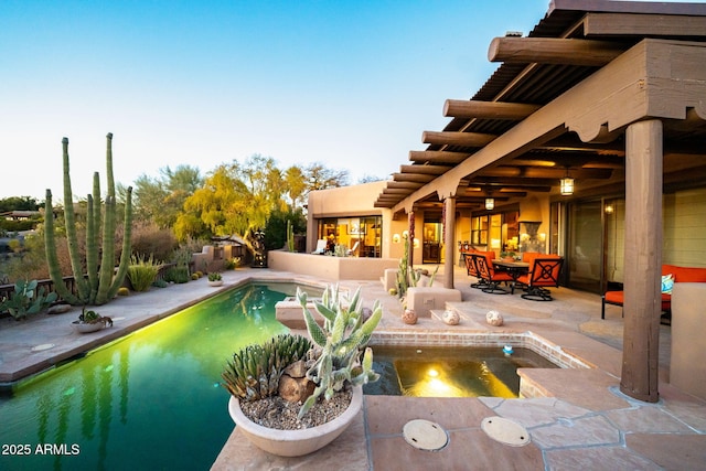 pool at dusk with a jacuzzi and a patio area