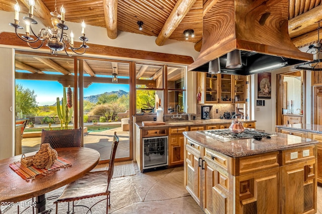 kitchen featuring wine cooler, light stone counters, a center island, wooden ceiling, and stainless steel gas stovetop