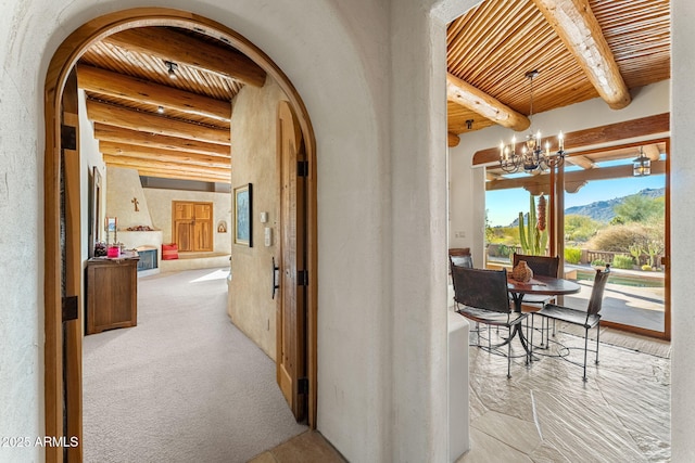 corridor featuring beamed ceiling, a mountain view, wooden ceiling, and an inviting chandelier