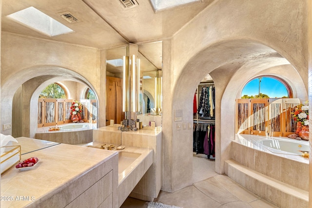 bathroom featuring vanity, tiled bath, and tile patterned flooring