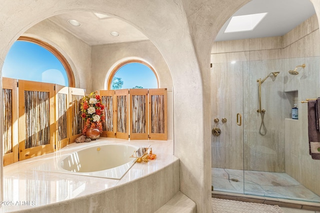 bathroom featuring shower with separate bathtub and a skylight