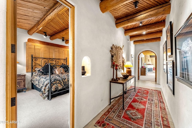 corridor featuring beamed ceiling, carpet flooring, and wooden ceiling