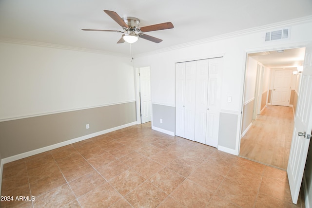 unfurnished bedroom with crown molding, a closet, and ceiling fan