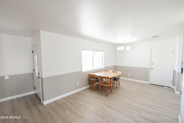 dining area with an inviting chandelier and light hardwood / wood-style flooring