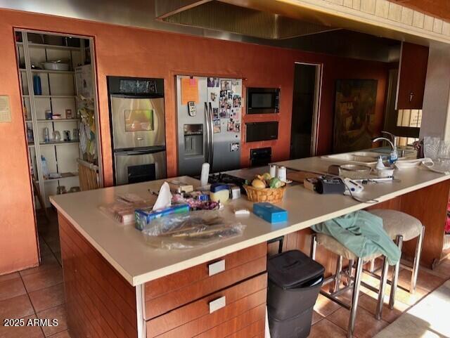 kitchen featuring sink, kitchen peninsula, stainless steel appliances, and light tile patterned flooring