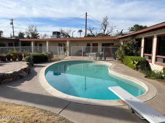 view of swimming pool with a diving board and a patio