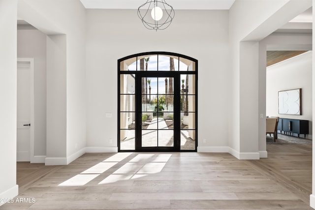 foyer with a notable chandelier, wood finished floors, and baseboards