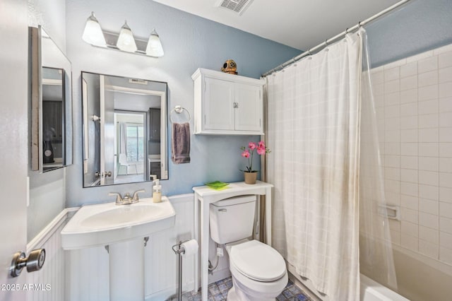 5133 E Keresan St, Phoenix, AZ 85044 - bathroom featuring toilet, shower / bath combination with curtain, and wainscoting