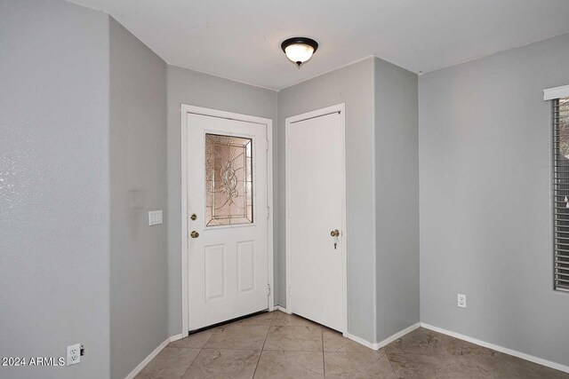 doorway with baseboards and light tile patterned floors