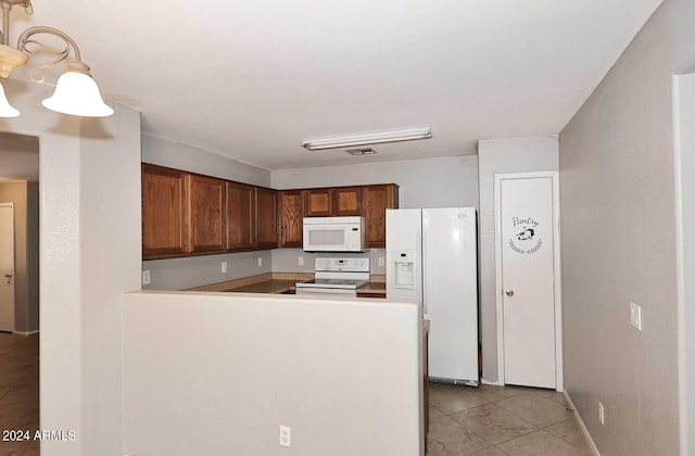 kitchen featuring light tile patterned floors, a peninsula, white appliances, visible vents, and brown cabinetry