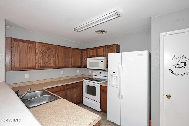 kitchen featuring white appliances, visible vents, brown cabinetry, light countertops, and a sink