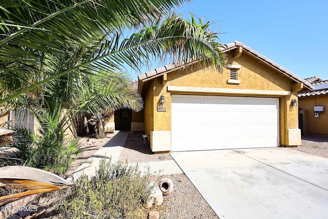 view of front of house with driveway, an attached garage, a tile roof, and stucco siding