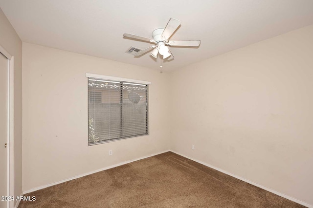 carpeted spare room featuring ceiling fan, visible vents, and baseboards