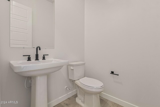 bathroom with toilet, sink, and hardwood / wood-style floors