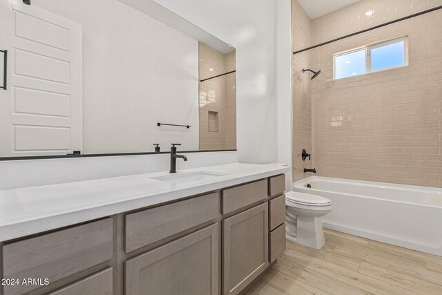 full bathroom featuring toilet, vanity, tiled shower / bath, and wood-type flooring