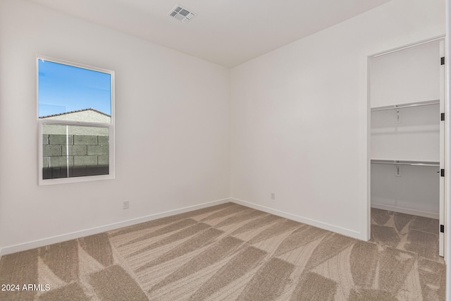 unfurnished bedroom featuring a spacious closet, carpet floors, and a closet