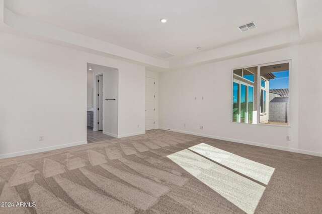 carpeted empty room featuring a tray ceiling