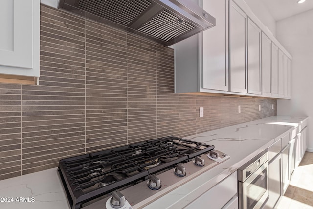 kitchen with white cabinetry, light stone countertops, appliances with stainless steel finishes, and custom range hood