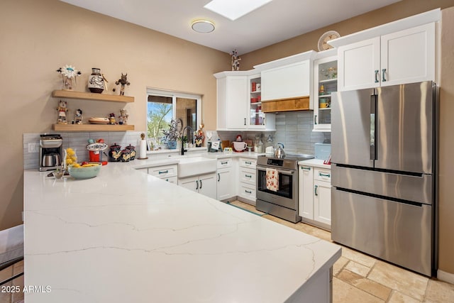 kitchen with backsplash, light stone countertops, stone tile floors, stainless steel appliances, and a sink