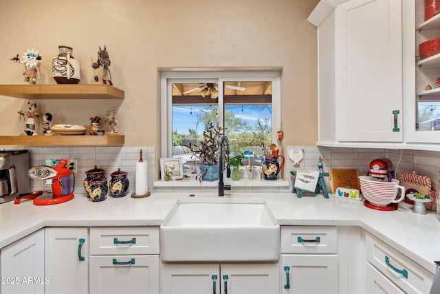 kitchen featuring backsplash, white cabinets, open shelves, and a sink