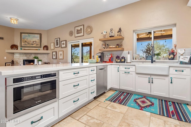 kitchen featuring white cabinetry, stainless steel oven, light countertops, and stone tile flooring