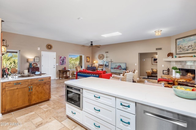 kitchen with visible vents, light stone counters, stone tile flooring, open floor plan, and a tile fireplace