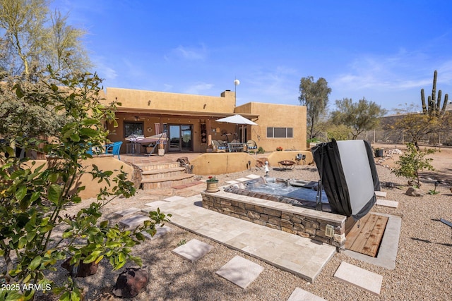 rear view of house featuring stucco siding and a patio area