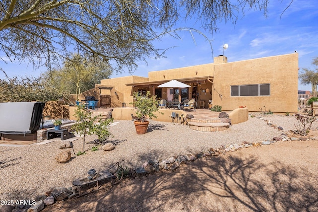 back of house with stucco siding, fence, a chimney, and a patio area