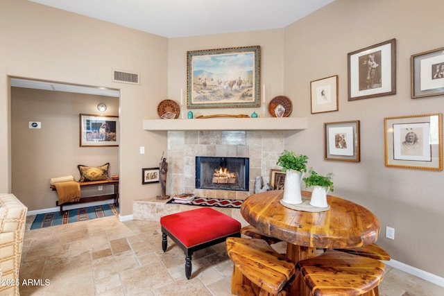 interior space with stone tile flooring, baseboards, visible vents, and a tile fireplace