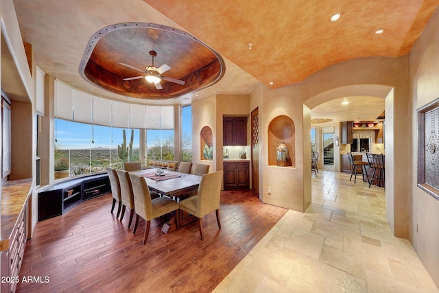 dining room featuring a raised ceiling, hardwood / wood-style flooring, and ceiling fan