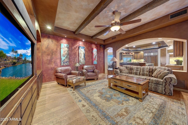 interior space with beam ceiling, ceiling fan, and light wood-type flooring