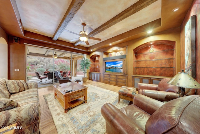 living room with ceiling fan, hardwood / wood-style flooring, built in features, and beamed ceiling