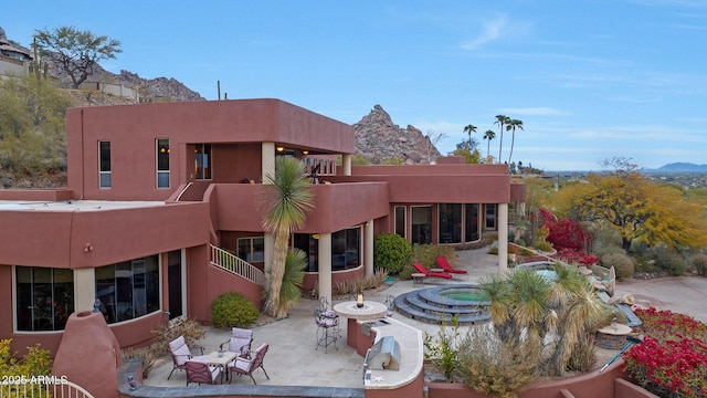 exterior space featuring a mountain view, a patio area, and a hot tub