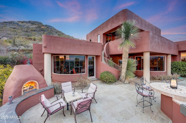 patio terrace at dusk featuring exterior fireplace