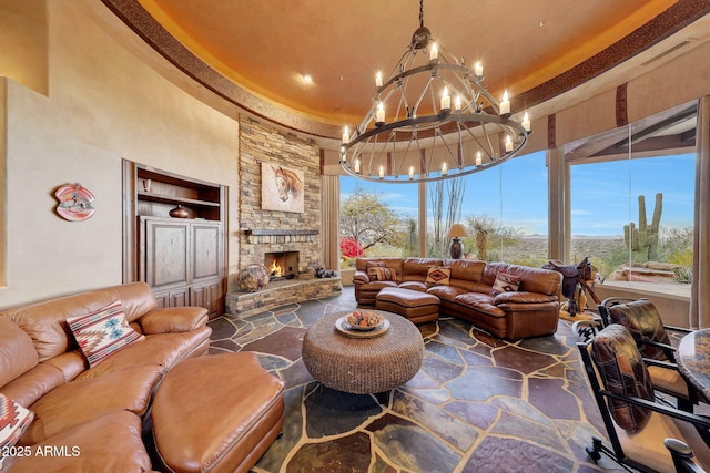 living room with built in features, a stone fireplace, a towering ceiling, and a notable chandelier