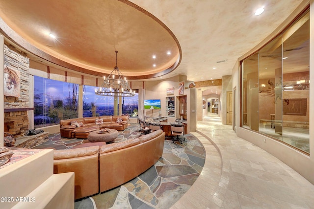 living room featuring an inviting chandelier, a fireplace, and a raised ceiling